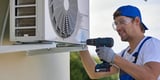 Smiling HVAC worker repairing an AC unit