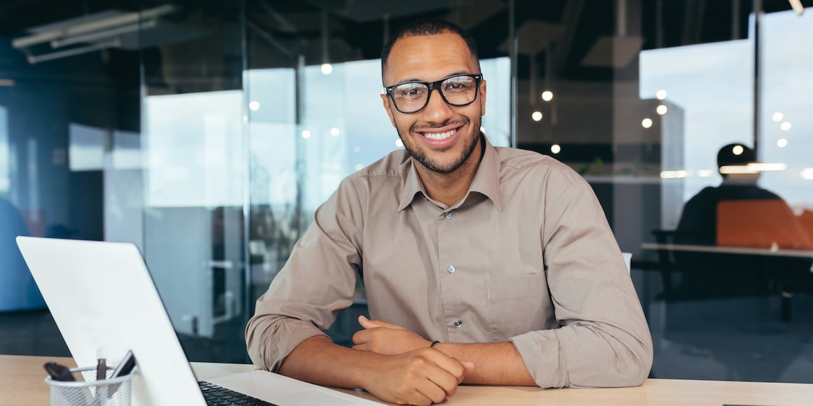 Smiling business owner in front of his laptop because his all-in-one fleet management system simplifies his daily workload
